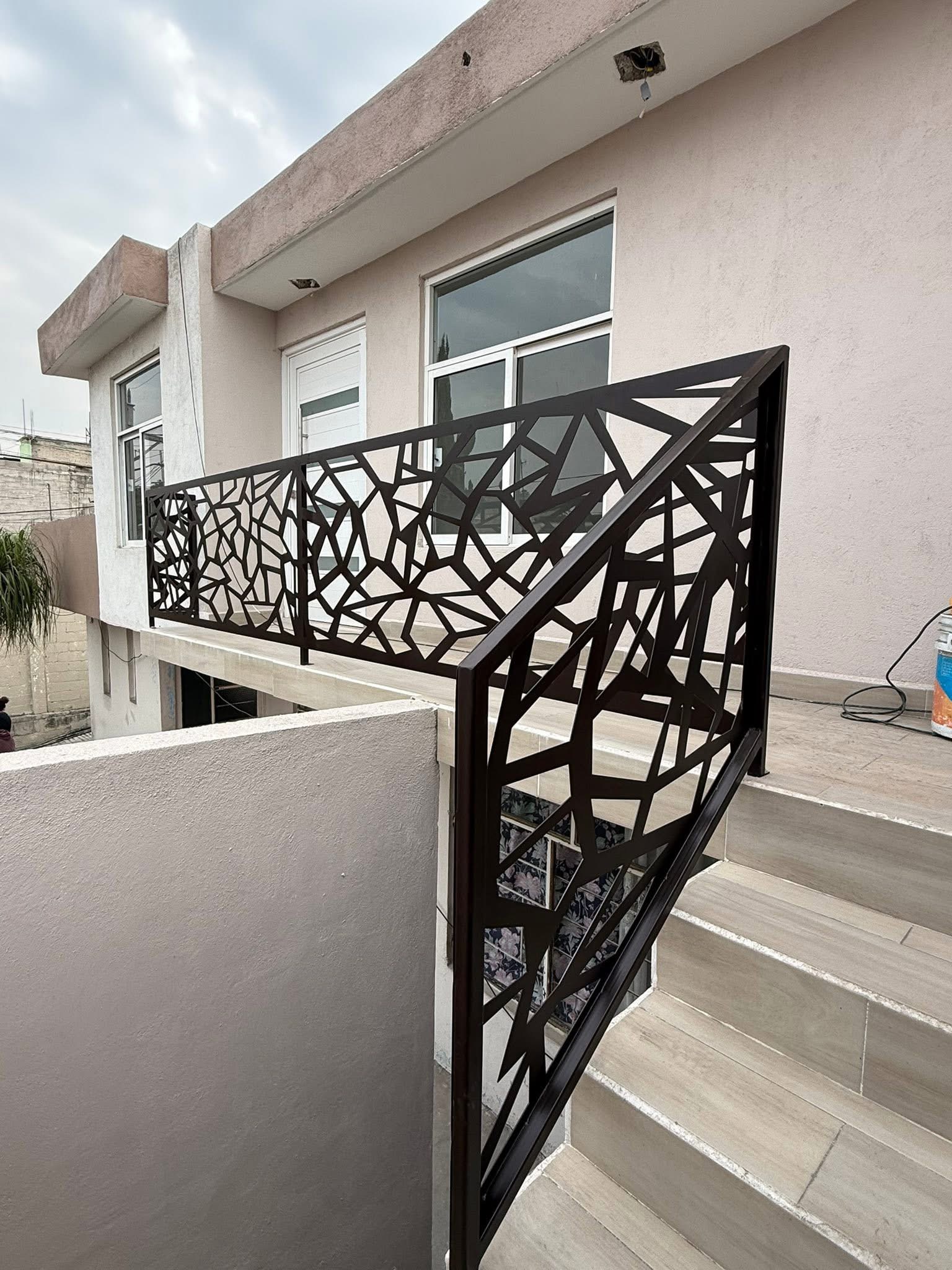 Barandal geométrico negro instalado junto a una escalera